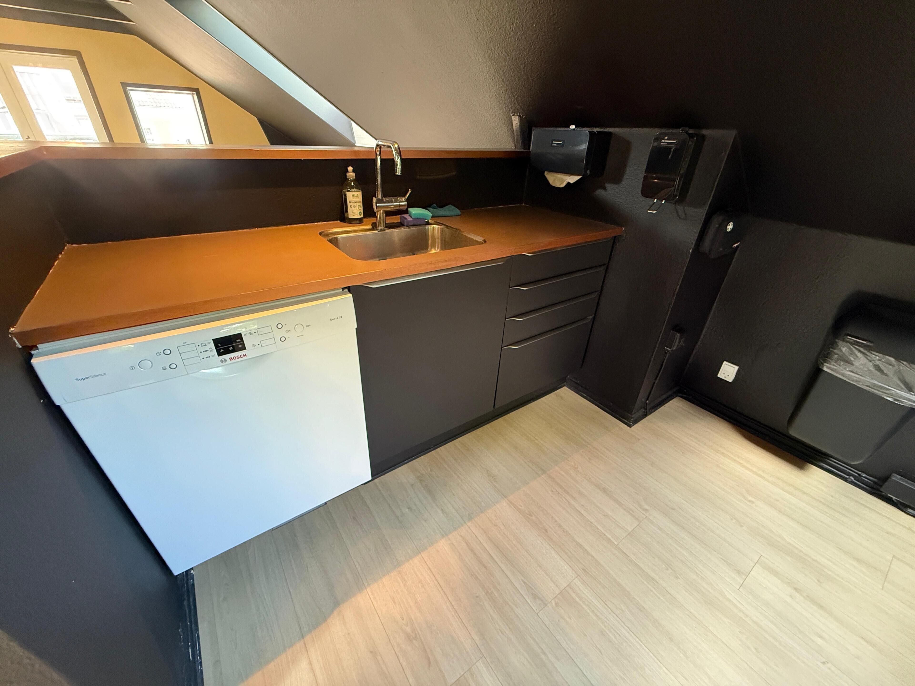 Una cocina compacta equipada con lavavajillas, un lavamanos y horno empotrado.