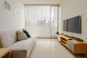 Ein modernes Wohnzimmer mit einer Couch, einem Fernseher, einem Holztisch und einer Schiebetür aus Glas.