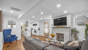 En moderne stue med en grå sofa, en blå lænestol og en pejs.