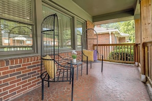 A covered patio with brick walls, large windows, and two wicker chairs with cushions. - Spacious Atlanta Retreat/2 Kitchens/ Sleeps 12/ 8 Min to Mercedes Benz (Atlanta)