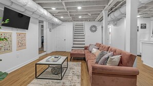 En moderne stue med sofasæt, sofabord og fjernsyn monteret på væggen.