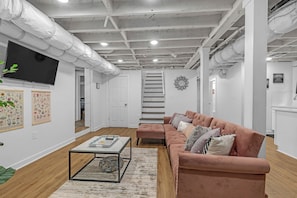 A modern living room with a sofa set, a coffee table, and a TV mounted on the wall. - Spacious Atlanta Retreat/2 Kitchens/ Sleeps 12/ 8 Min to Mercedes Benz (Atlanta)