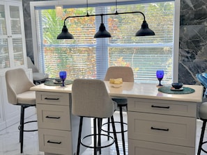 Ein Essbereich mit Tisch, Stühlen und einem Fenster mit Jalousien.