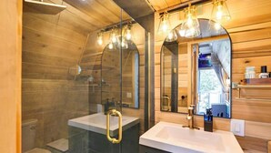 A modern bathroom with a glass shower enclosure, two sinks, and a large mirror. - Eagle’s Nest Couples Escape w/ Hot Tub & Firepit (Cherokee)