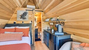 A cozy cabin interior with a bed, a kitchenette, and a dining area. - Eagle’s Nest Couples Escape w/ Hot Tub & Firepit (Cherokee)
