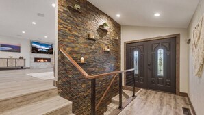 Ein modernes Interieur mit einer Wand aus Naturstein, einer Treppe mit Metallgeländern und einer dunklen Holztür.