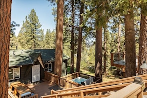 Una cabaña con terraza, jacuzzi y escalera de madera.