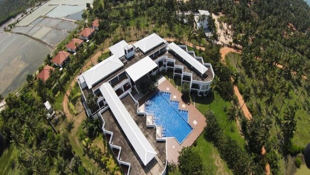 A resort with a swimming pool, multiple buildings, and surrounding greenery.