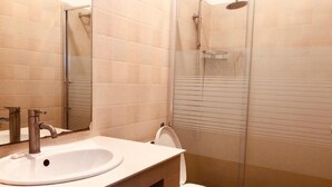 A bathroom with a sink, mirror, toilet, and shower.