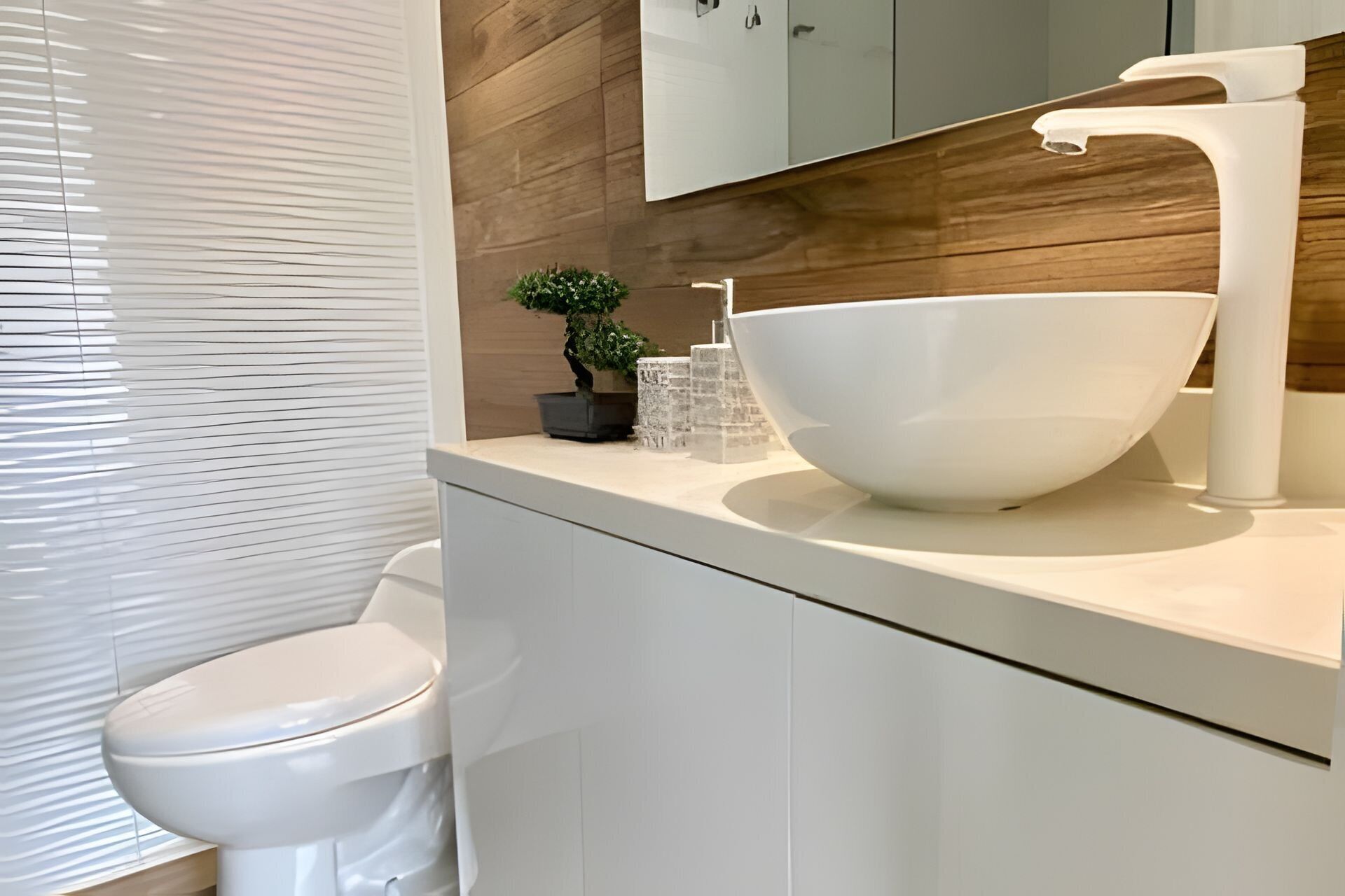Une salle de bain moderne avec des toilettes blanches, un grand lavabo blanc, un mur en bois et un miroir au-dessus du lavabo.