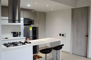 Una cocina moderna con estufa a gas, electrodomésticos de acero inoxidable y encimera blanca.