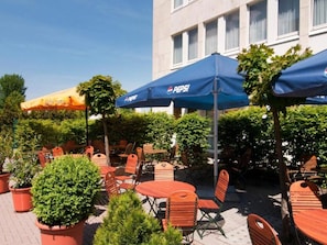 Un espace extérieur aménagé avec des tables, des chaises, des parasols et des plantes en pot.