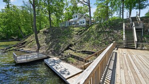 A house with a dock extending into a body of water, surrounded by trees.