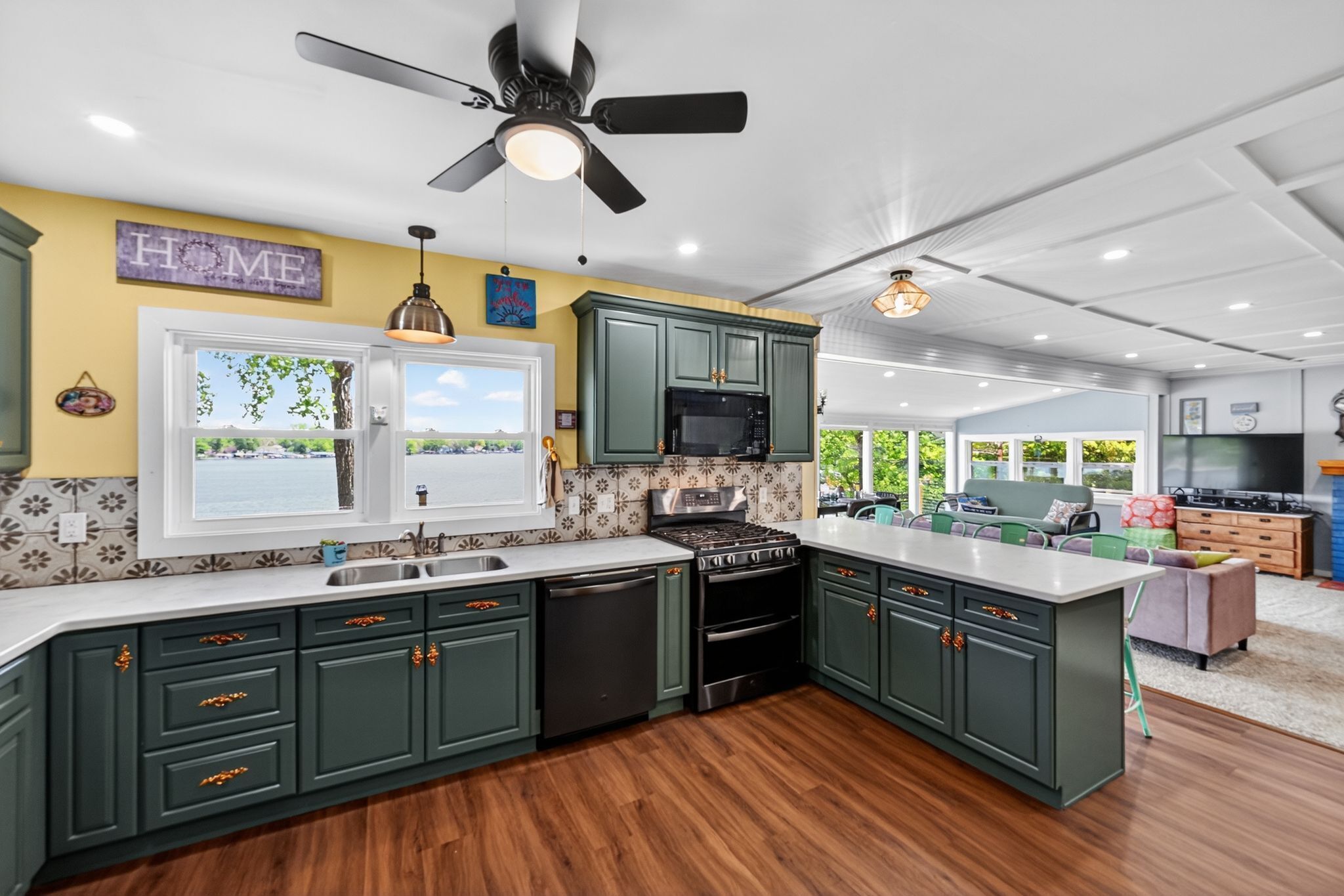 Une cuisine moderne avec des meubles de couleur vert foncé, un îlot central, une cuisinière et un four à micro-ondes.
