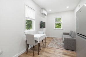 A compact living space with a dining table, a sofa, and a refrigerator.
