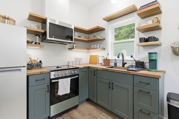 A kitchen with built-in appliances, wooden shelves, and a window with a view.