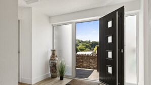 Ein modernes Interieur mit einer großen Schiebeglasdoor, die auf einen Balkon mit Steinwand und Bepflanzung führt.