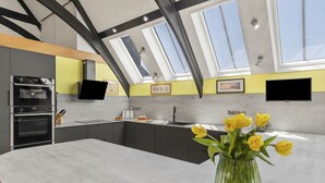 Eine moderne Küche mit Dachfenstern, einer großen Kochinsel und einer Vase mit gelben Blumen.