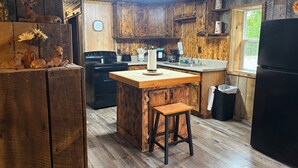 Eine rustikale Küche mit Holzausstattung, einer zentralen Kochinsel, einem Herd und einem Kühlschrank.