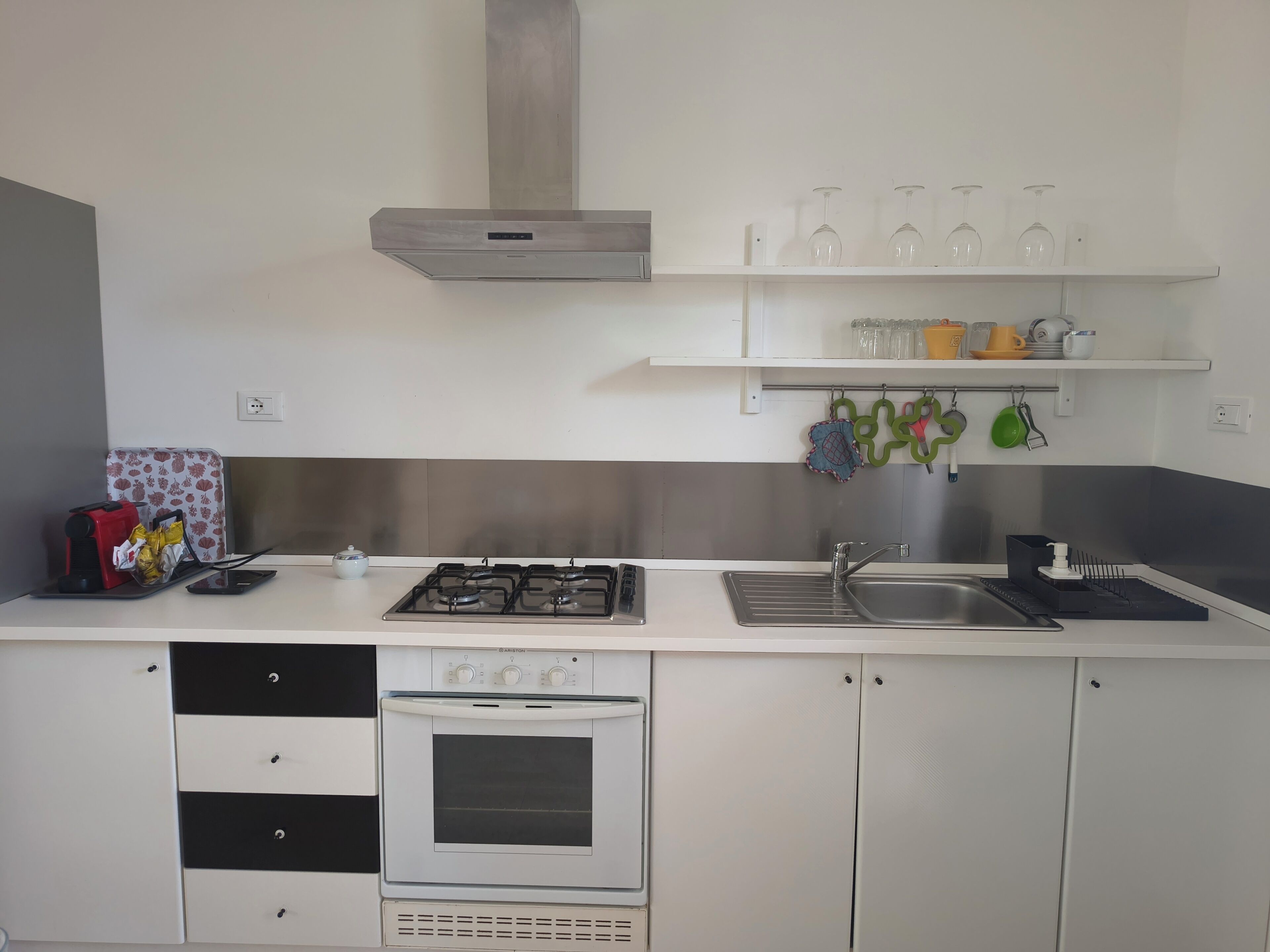 Cocina compacta con estufa a gas, horno y pileta. Cuenta con alacenas y una mesada con distintos elementos de cocina.