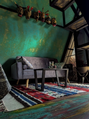 A room with a sofa, a coffee table, a patterned rug, and a wall with decorative masks.