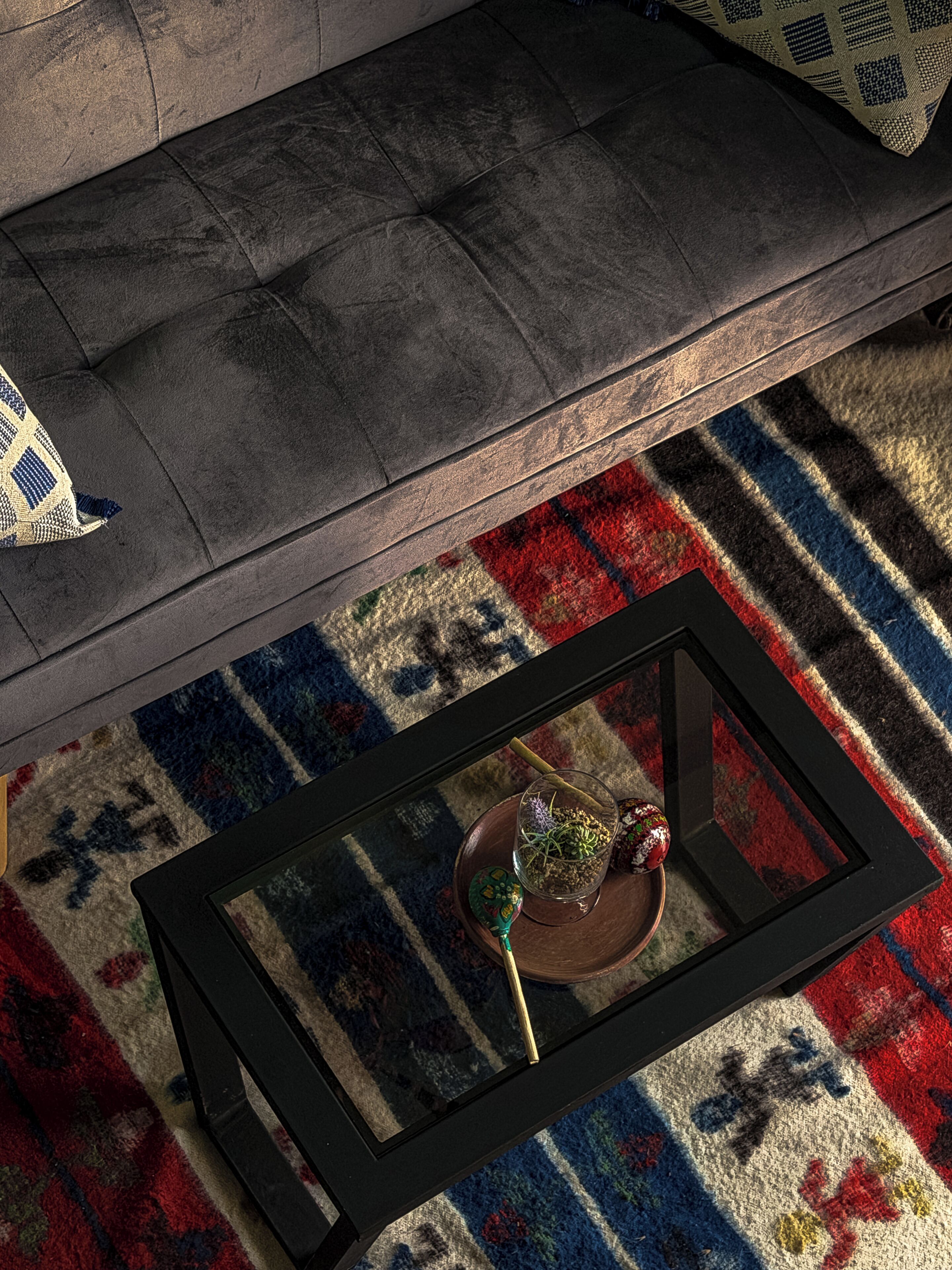 Un salon moderne avec une table basse noire, un tapis à motifs et un canapé gris.
