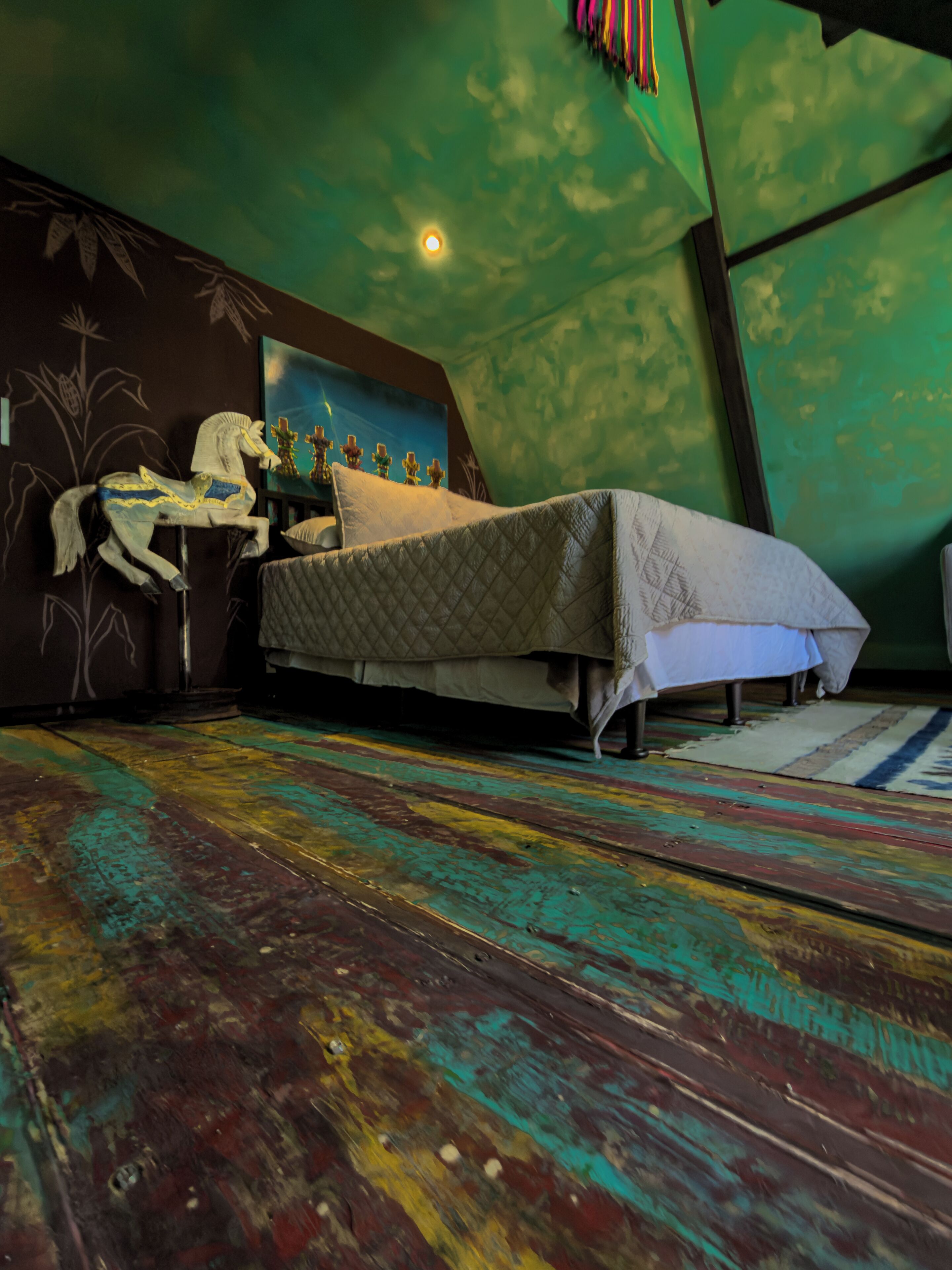 A room with a bed, a small table, and a wall with a mural.