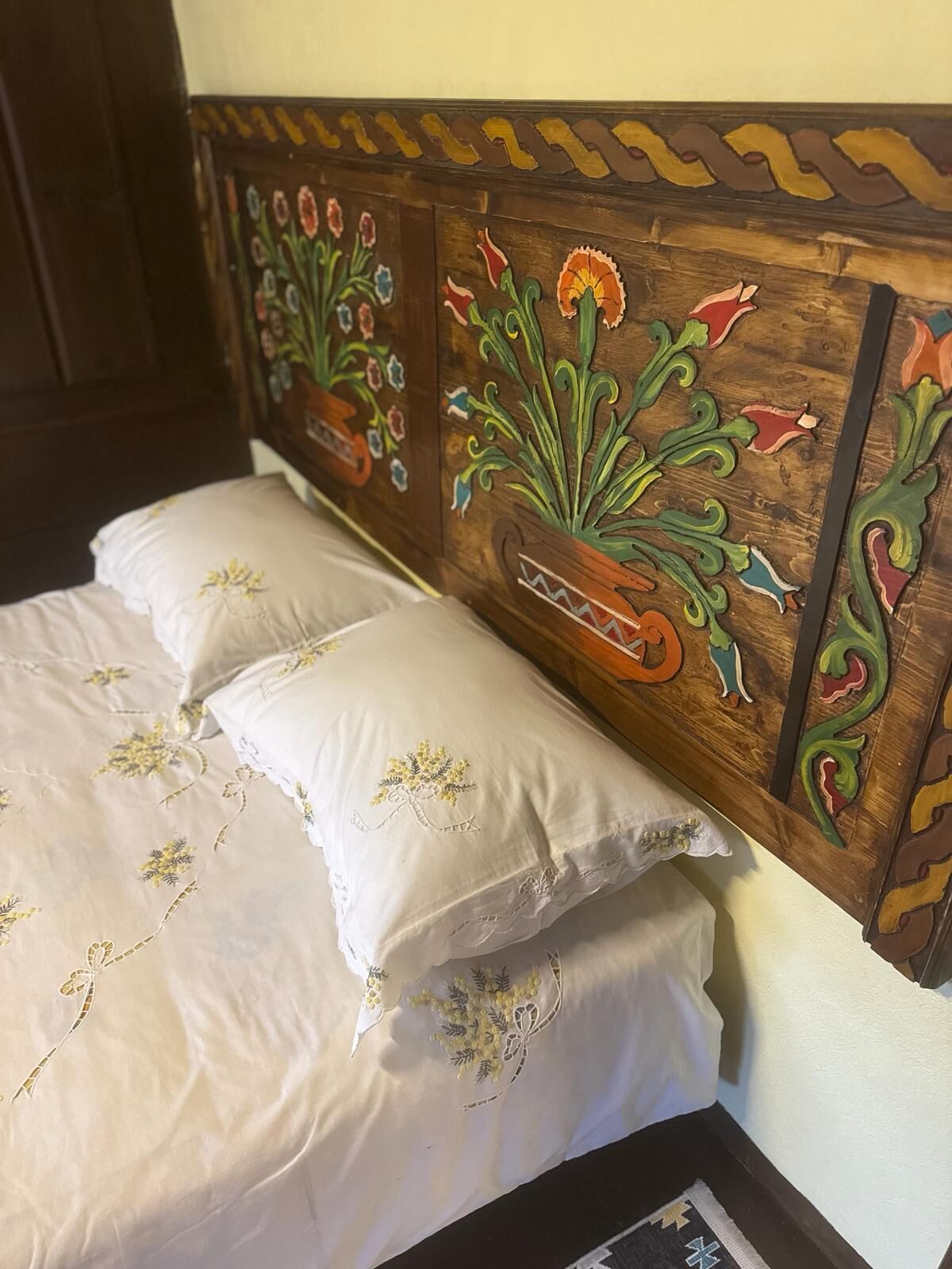 Una cama con almohadas de estampado floral y un cabecero de madera decorado con motivos florales.