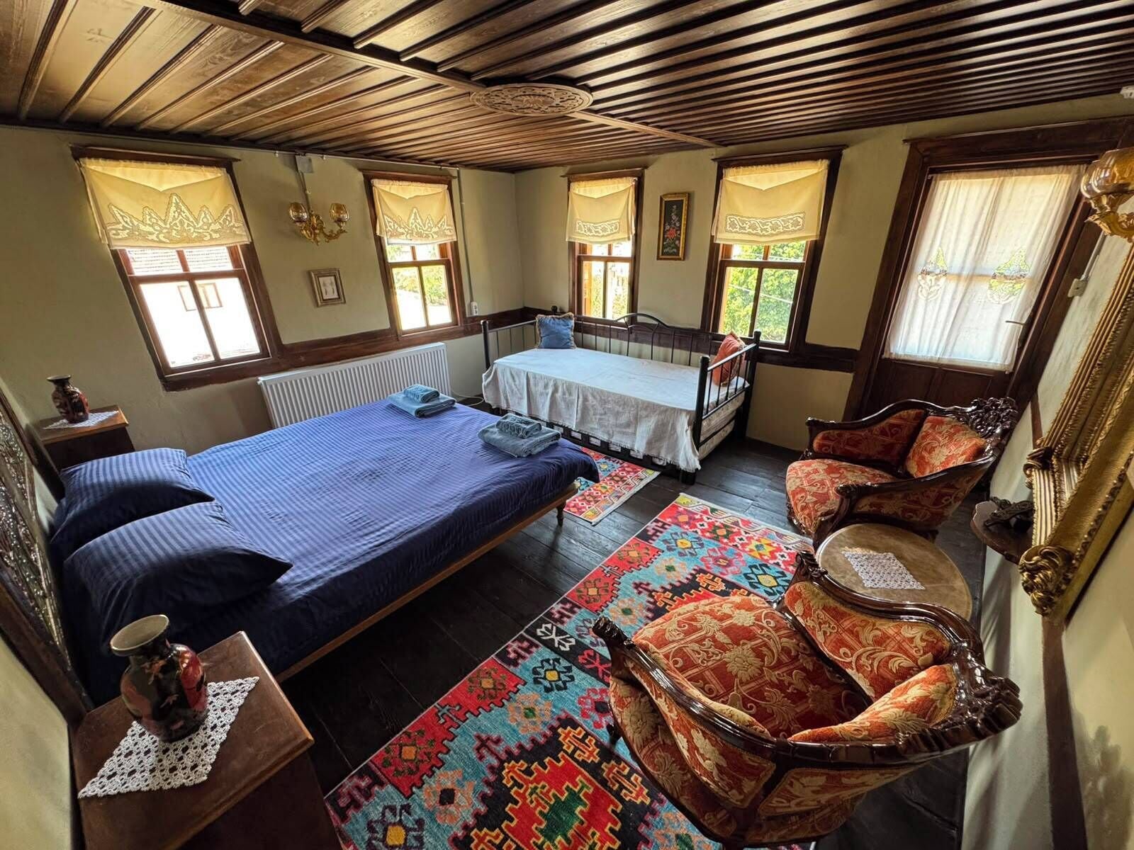 Un dormitorio con dos camas, techo de madera y una alfombra estampada.
