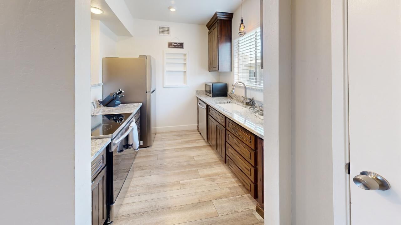 Une petite cuisine équipée d’un réfrigérateur, d’un four à micro-ondes et de meubles de rangement en bois.