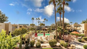 A resort with multiple-story buildings, a swimming pool, and palm trees.