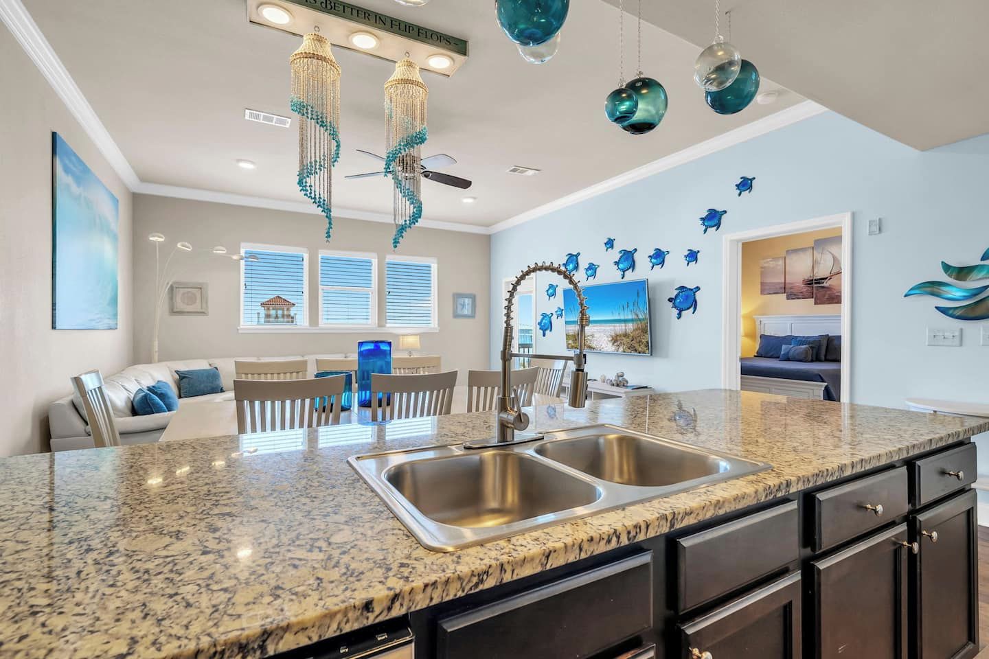 A modern kitchen with granite countertops, stainless steel appliances, and decorative hanging lights.
