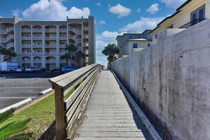 A wooden boardwalk leading to a multi-story building with balconies. - Luxe 3BR Gulf View l Steps to Beach + Pool (Miramar Beach)