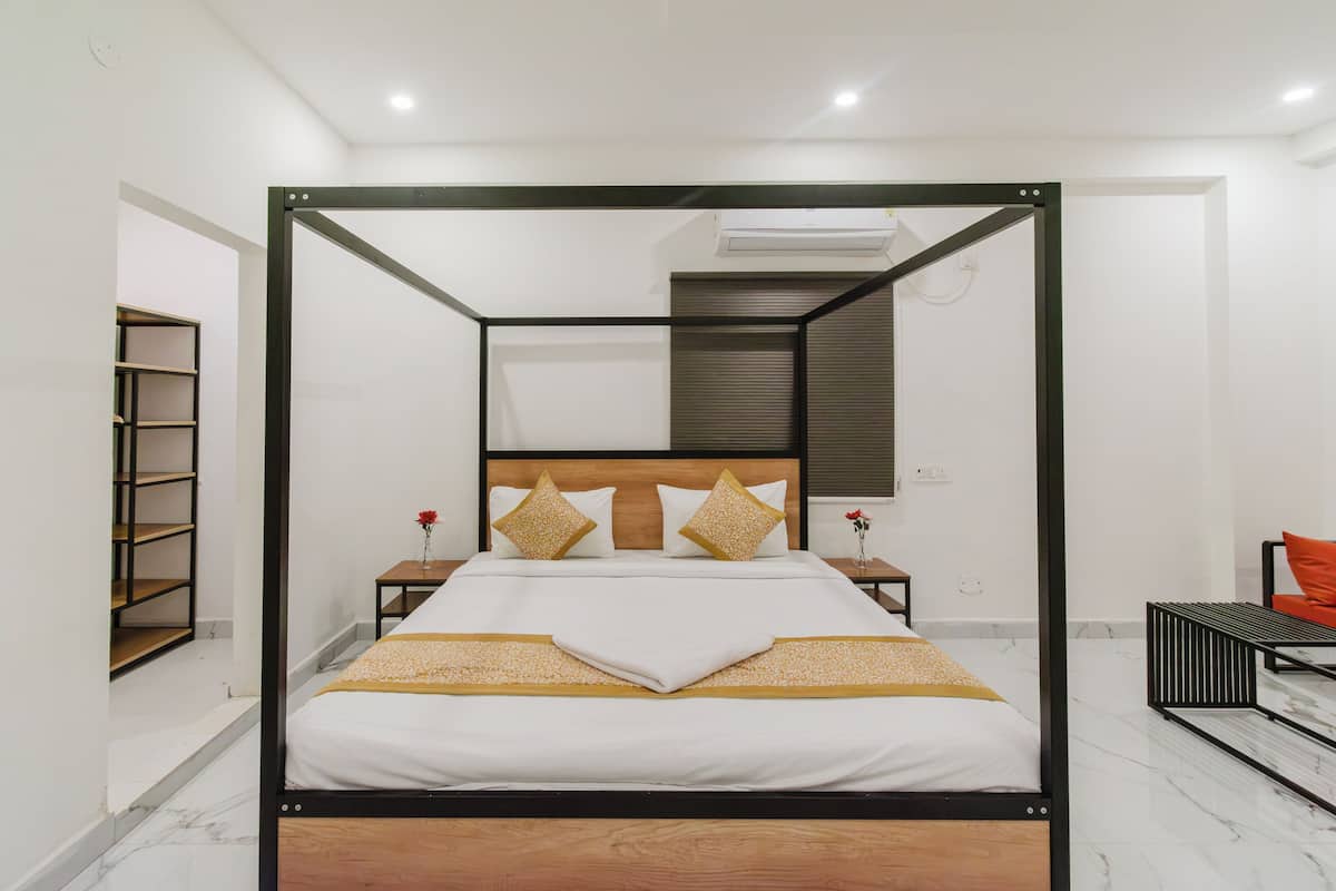 Uma cama de dossel com cabeceira de madeira, roupa de cama branca e almofadas decorativas.