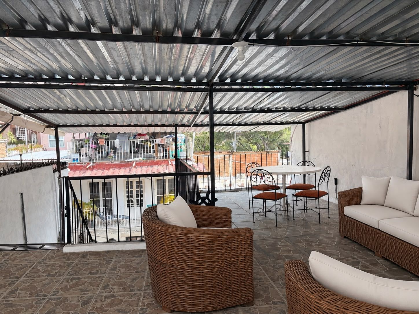 A covered outdoor seating area with wicker furniture and a table.