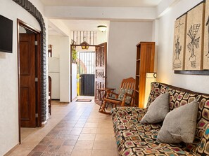 A living room with a patterned sofa, a wooden cabinet, and a dining area with chairs. - Romantic Zone 1BR · Rooftop Terrace · AC · WiFi (Puerto Vallarta)