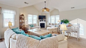 A spacious living room with a high ceiling, a fireplace, and a television. - Corolla Retreat w/ Views, Hot Tub & Amenities (Corolla)