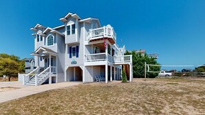A two-story house with a balcony, a covered porch, and a flag. - Corolla Retreat w/ Views, Hot Tub & Amenities (Corolla)