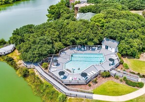 Ein sechseckiger Pool mit einer Liegefläche, umgeben von üppiger Vegetation und einem See.