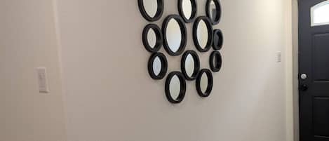 A hallway with a tiled floor and a wall-mounted mirror arrangement.