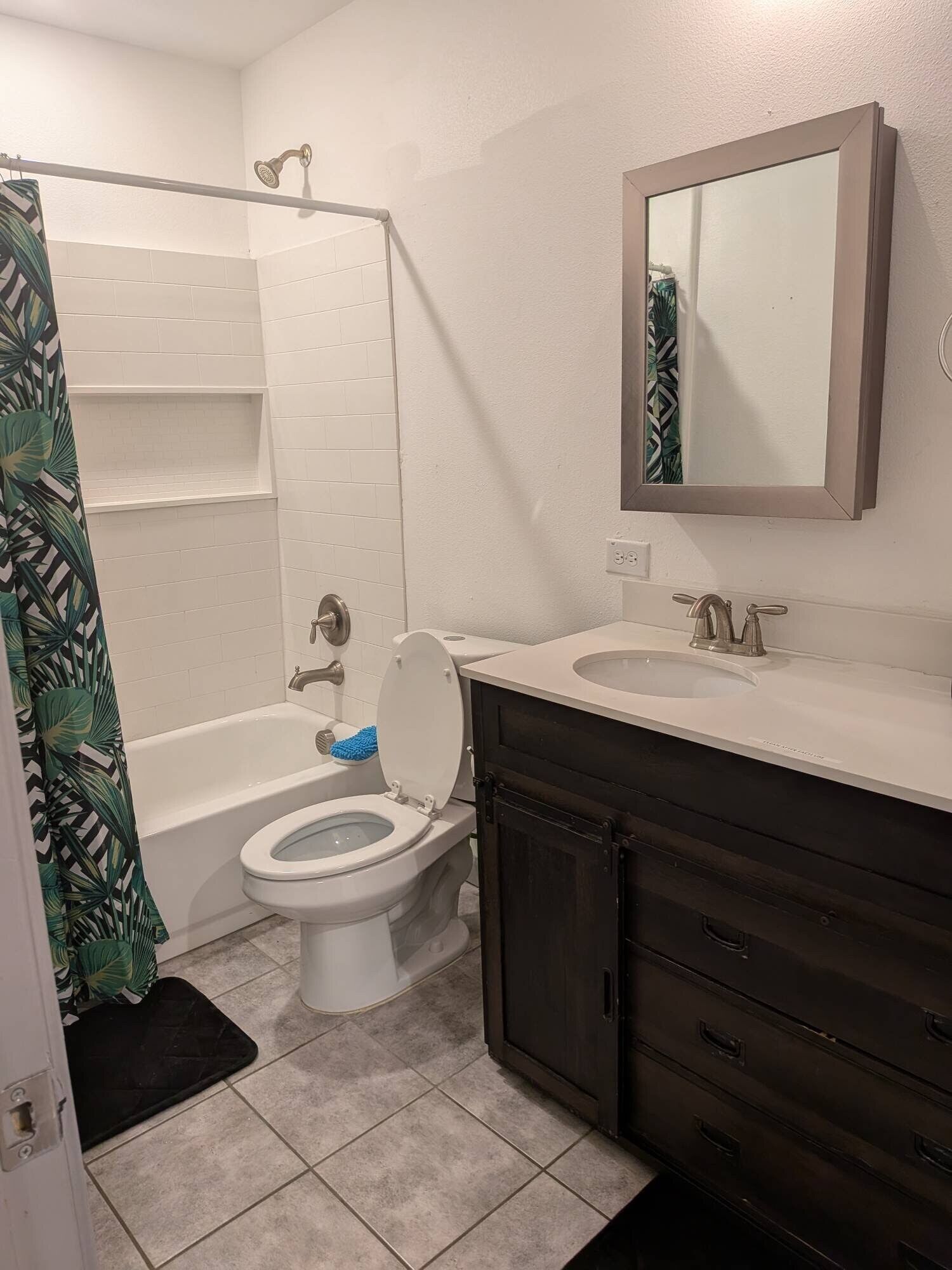 A bathroom with a toilet, sink, mirror, and shower.