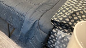Een slaapkamer met een bed, een bank, een spiegel en een raam met gordijnen.