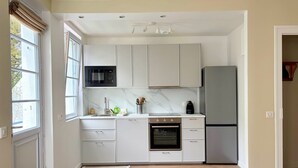 Een moderne keuken met witte kasten, een inbouwoven, een magnetron en een koelkast.