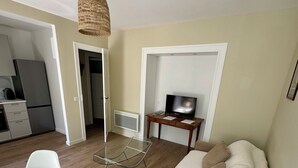 Een moderne woonkamer met een bank, een eettafel en een televisie op een dressoir.