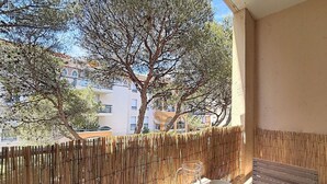 A balcony with a bamboo fence, a table with four bowls, and a bench. - Reflet Azur - Modern Studio with Sea View Balcony (Fréjus)