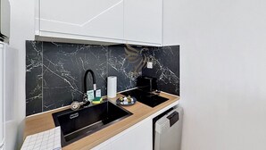 A modern kitchen with a black marble backsplash, a wooden countertop, a black sink, and a dishwasher. - Reflet Azur - Modern Studio with Sea View Balcony (Fréjus)