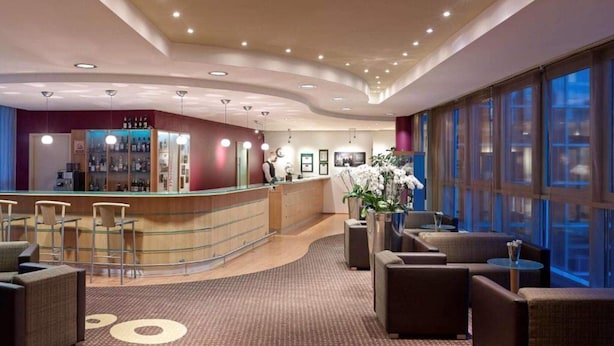 A hotel lobby with a reception desk, seating area, and large windows. - 2 Person Holiday Park Home in Dortmund (Dortmund)