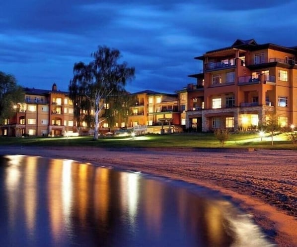 Un hôtel à plusieurs étages doté de balcons, d’un bassin d’eau aux reflets changeants et d’espaces extérieurs bien éclairés.