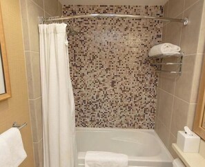 Une douche avec un mur recouvert de mosaïques, un rideau blanc et un porte-serviettes.