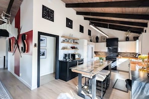 Una cucina moderna con isola centrale, mobili neri e soffitto in legno.